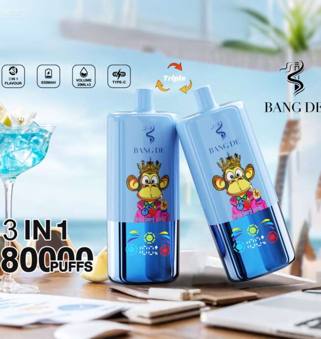 Zwei Bang De 3-in-1-Einweg-Vaporizer mit einem Cartoon-Affen-Design, auf einem Tisch mit einem Cocktail und elektronischen Geräten platziert, bieten Blaubeereisgeschmack und 80.000 Züge.