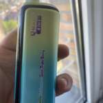 A colorful vape device with gradient teal to purple, labeled “Quads 4 in 1” and “Vanilla Ice Cream – Sour Triple Berry,” held near a window.