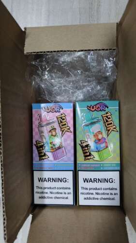 Two colorful boxed vape devices inside a cardboard box, each featuring a cartoon monkey image and flavor names; packaged with clear plastic bags and a warning label about nicotine.